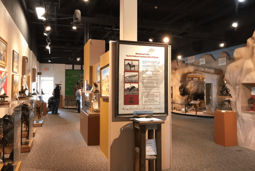 Interior of a museum featuring displays about North Dakota's cowboy history, with exhibits and informational signage.