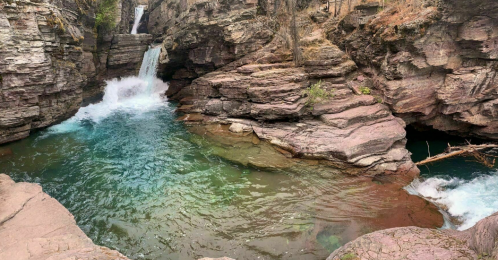 A serene natural scene featuring a waterfall cascading into a turquoise pool surrounded by rocky cliffs.