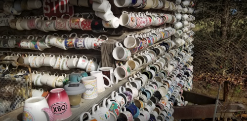 A wall covered with an array of colorful mugs displayed in various orientations.
