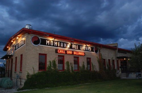 Exterior of Montana Ale Works building at dusk, featuring a sign and cloudy sky.