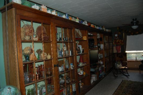 A wooden display cabinet filled with various decorative items and glassware, set in a cozy room.