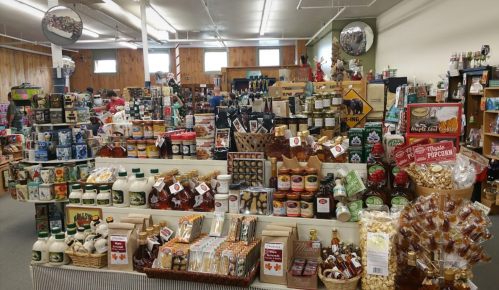 A vibrant display of various local products, including maple syrup, snacks, and gourmet items in a cozy store.