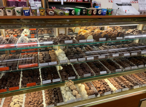A display case filled with a variety of chocolates and confections, neatly arranged on multiple shelves.