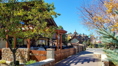 A sunny street view featuring a rustic building, trees, and a sign for "The Christie" in a charming neighborhood.