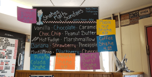 Menu board displaying various shakes, malts, and sundaes with flavors like vanilla, chocolate, and maple nut.