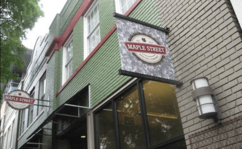 Exterior of a building with green and red walls, featuring a sign that reads "Maple Street."