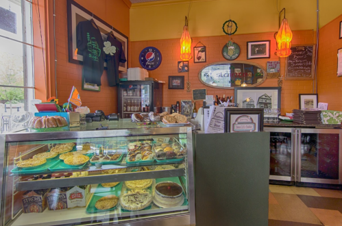 A cozy café interior featuring a display case of pastries, colorful decor, and warm lighting.
