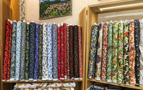 A display of colorful fabric rolls featuring various floral and bird patterns in a craft store.