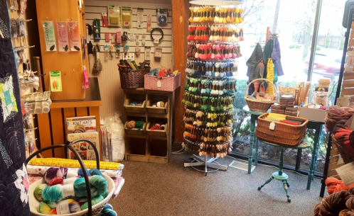 A cozy craft store interior filled with colorful yarn, embroidery floss, and various crafting supplies on display.