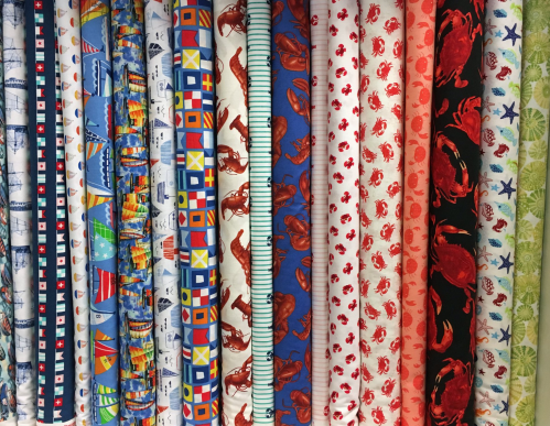 A colorful display of various fabric rolls featuring nautical and crab patterns.