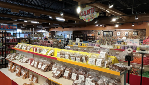 A colorful candy store interior with shelves of assorted candies and snacks, bright lighting, and a welcoming atmosphere.