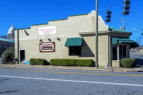 A small restaurant building with green awnings and a sign reading "Cotham's in the City" on a sunny day.