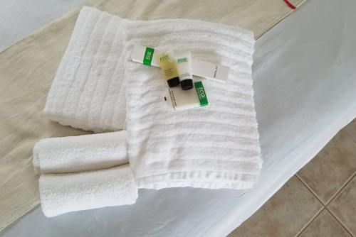 A neatly arranged set of white towels and eco-friendly toiletries on a bed.