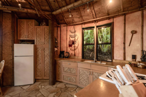 Cozy kitchen with bamboo accents, stone floor, and large window overlooking lush greenery.