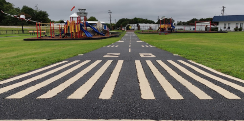A playground path designed to resemble a runway, with striped markings and play structures on either side.