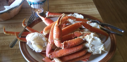 A plate of cooked crab legs, featuring orange shells and white meat, set on a wooden table.