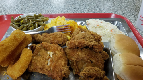 A tray of fried chicken, macaroni and cheese, green beans, coleslaw, two rolls, and fried okra.