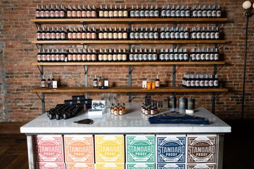 A display of various bottles and products on shelves and a table, set against a brick wall.