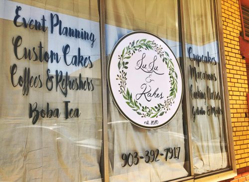 Window display for LuLu & Cakes featuring event planning, custom cakes, boba tea, and various desserts. Established 2020.