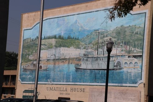 Mural depicting the Umatilla House and a steamboat on a river, surrounded by mountains and trees.