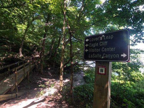 Signpost in a wooded area with directions to Lover's Leap, Eagle Cliff, Visitor Center, and LaSalle Canyon.