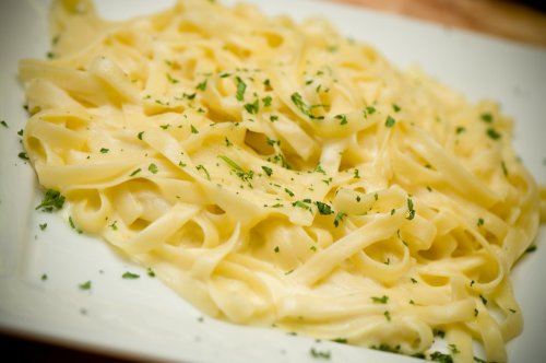 A plate of creamy fettuccine pasta garnished with fresh parsley.