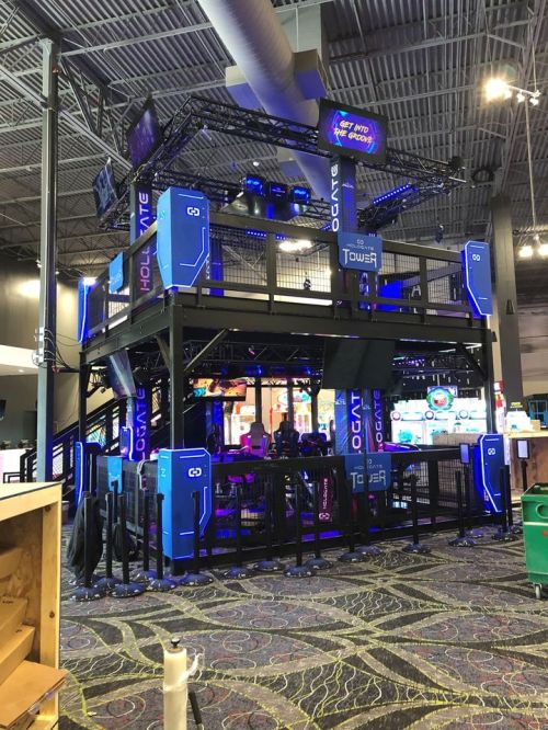 A multi-level gaming attraction with neon lights and a futuristic design, set in an entertainment venue.