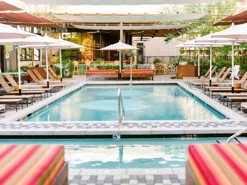 A serene pool area with lounge chairs, umbrellas, and greenery, creating a relaxing outdoor atmosphere.