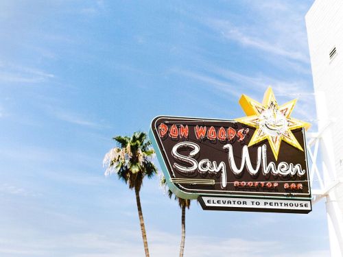 Sign for "Don Wood's Say When" rooftop bar with a star design and palm trees against a blue sky.