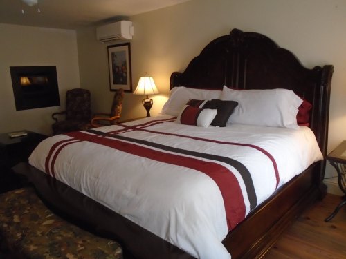 Cozy bedroom featuring a large bed with decorative pillows, a chair, and a lamp in a warm, inviting atmosphere.