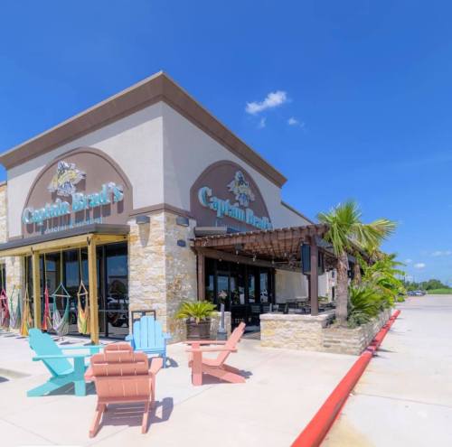 Exterior of Captain Brad's restaurant with colorful chairs, palm trees, and a clear blue sky.