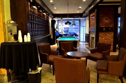 Cozy lounge area with brown chairs, a table, and a pool table, featuring a modern design and warm lighting.