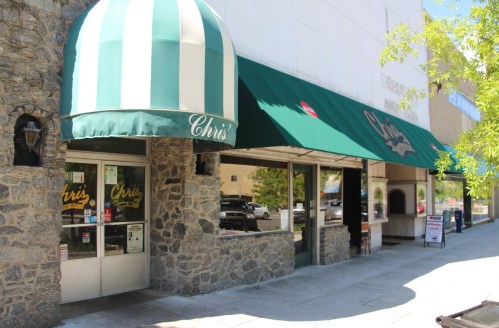 A storefront with a green and white striped awning, featuring the name "Chris" on the entrance and awnings.