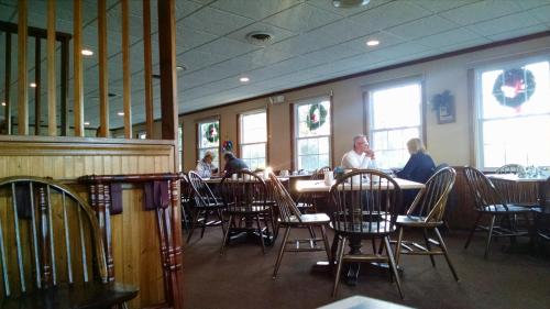 A cozy restaurant interior with wooden chairs, tables, and festive decorations, featuring diners engaged in conversation.
