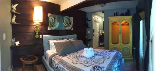 Cozy bedroom with a wooden accent wall, a bed with decorative pillows, and a vintage armoire. Soft lighting enhances the ambiance.