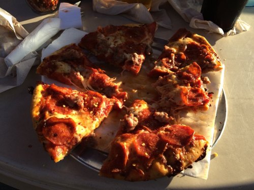 A plate of partially eaten pepperoni pizza with several slices missing, sitting on a table with napkins.