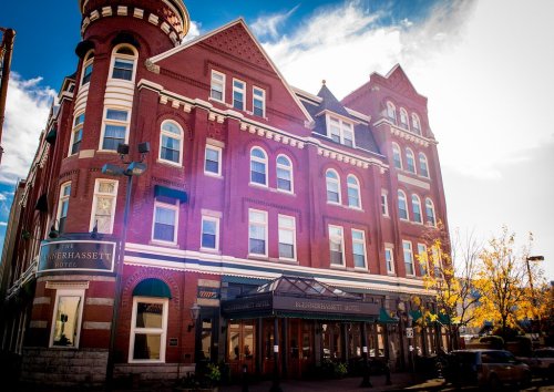 Historic Blennerhassett Hotel with red brick facade, large windows, and a turret, set against a bright blue sky.