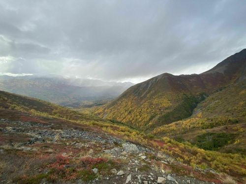 A scenic view of mountains and valleys, showcasing autumn foliage under a cloudy sky.