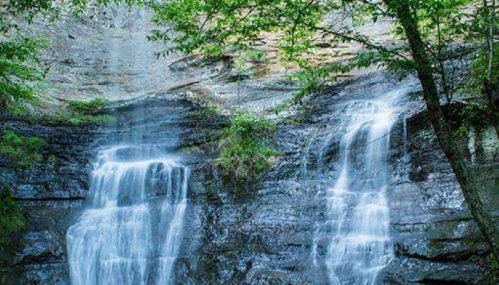 A serene waterfall cascading over rocky cliffs, surrounded by lush green trees and foliage.