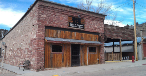 Historic stone building with wooden accents, featuring a sign for a business, set against a blue sky.