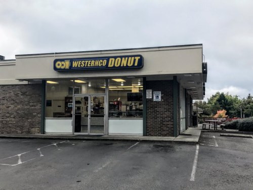 Exterior of Westernco Donut shop, featuring a large sign and glass entrance, set in a commercial area.