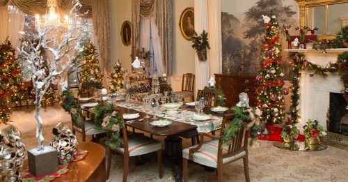 A beautifully decorated dining room for the holidays, featuring a festive table setting, Christmas tree, and elegant decor.