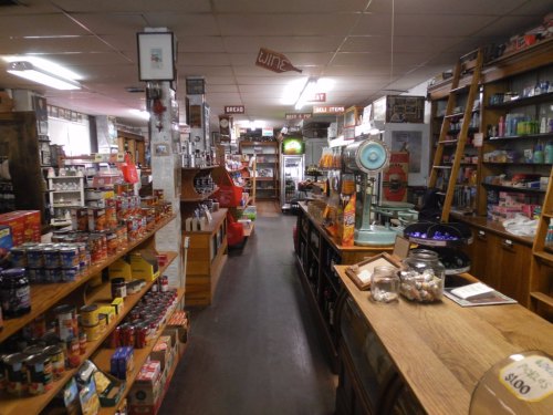 A cozy, vintage grocery store aisle filled with shelves of canned goods, snacks, and various products.