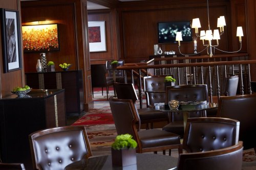 Elegant restaurant interior with dark wood paneling, stylish furniture, and decorative lighting.