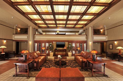 Elegant hotel lobby with a coffered ceiling, leather sofas, decorative lamps, and a patterned rug. Warm, inviting atmosphere.