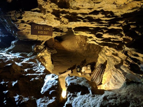 A dimly lit cave with a sign reading "Jesse James Hideout" and rocky formations surrounding the entrance.