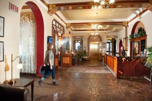 A woman walks through a stylish hotel lobby with elegant decor and a reception desk.