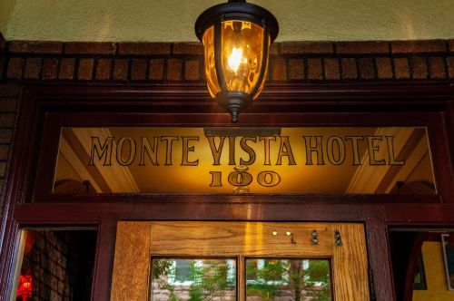 Sign above the entrance of the Monte Vista Hotel, featuring the hotel name and number 100, illuminated by a lantern.