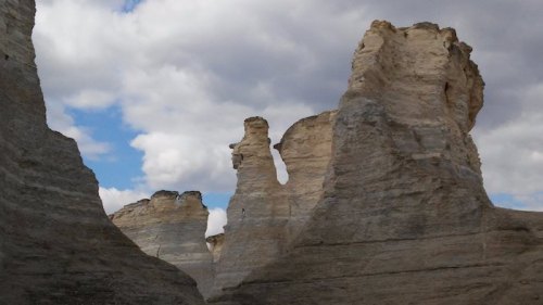 Rock formations rise against a cloudy sky, showcasing unique shapes and textures in a natural landscape.