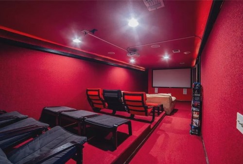 Cozy home theater with red walls, comfortable seating, and a large screen for movie viewing.